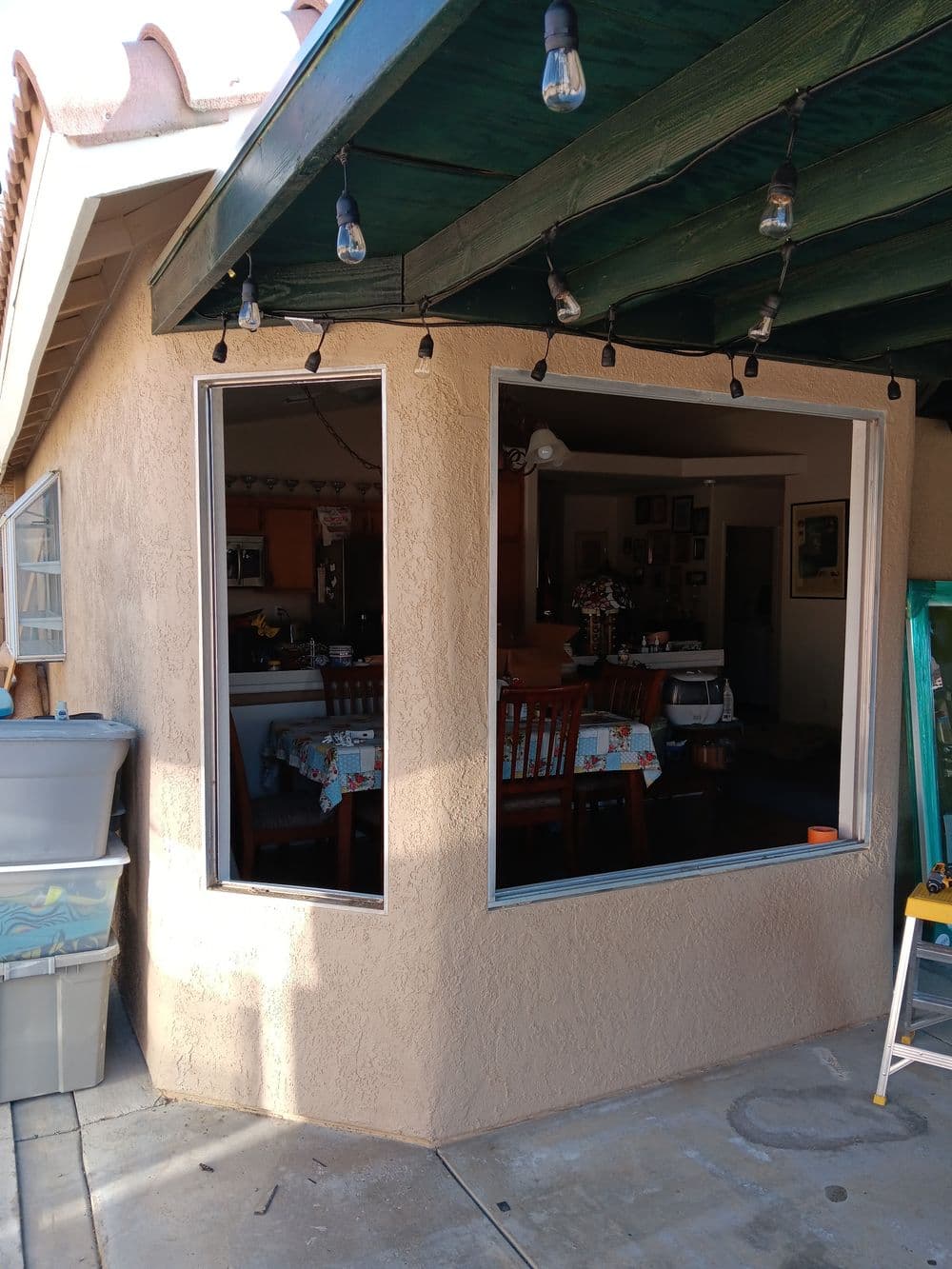 Modern outdoor dining area with string lights and large windows, showcasing interior decor.