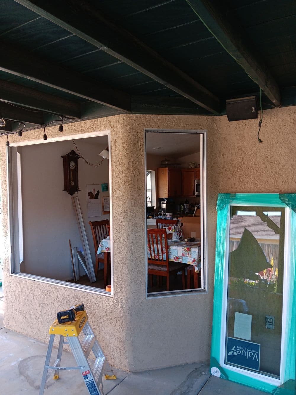 Home renovation showing a framed window opening with supplies and a kitchen in the background.