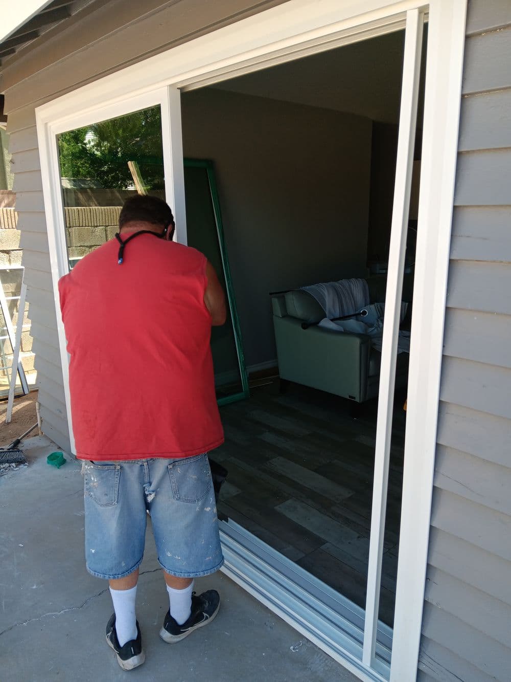 Man installing sliding glass door in home interior, showcasing renovation work.