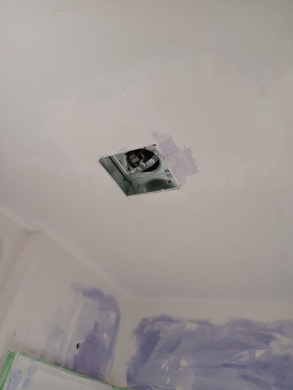 Ceiling vent opening in freshly painted room with purple wall patches.