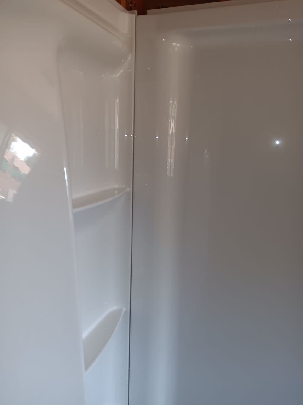 Clean white shower interior with built-in shelves and smooth finish.