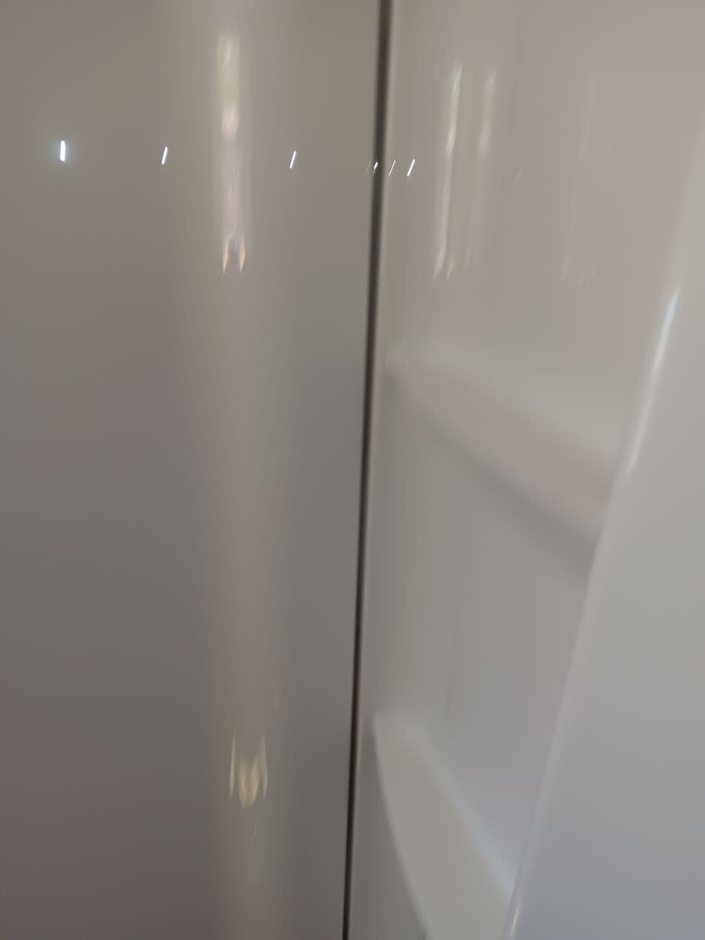 Interior view of a modern white refrigerator with shelves and a smooth finish.