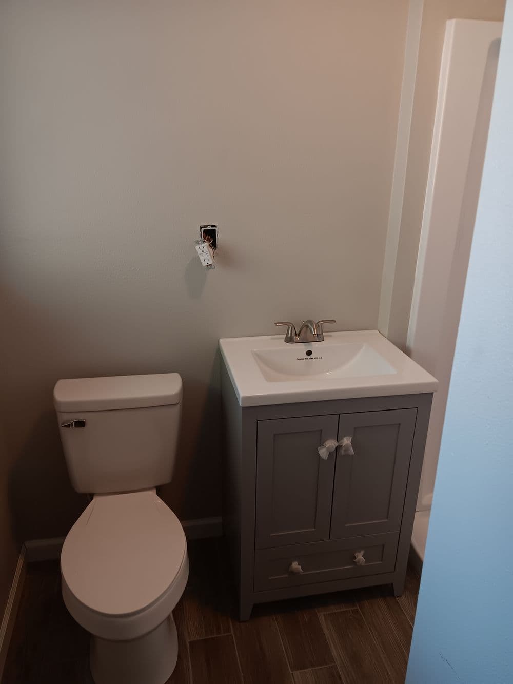 Compact bathroom featuring a modern gray vanity, toilet, and shower space.