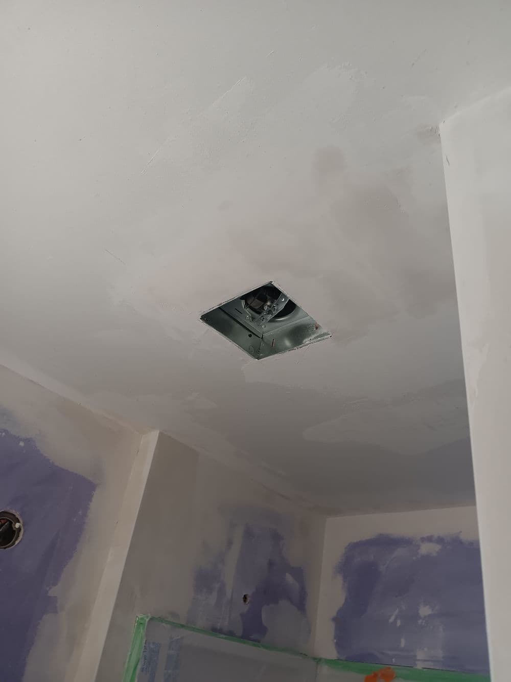 Ceiling with an unfinished drywall patch and a vent opening in the center, under construction.