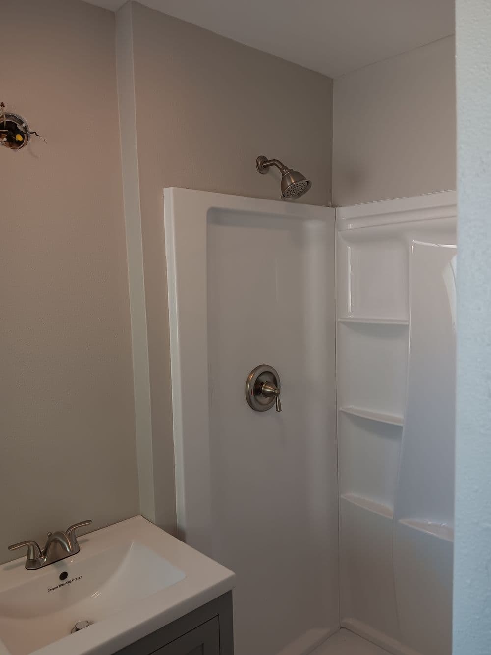 Modern bathroom shower with glass door, chrome fixtures, and gray vanity.