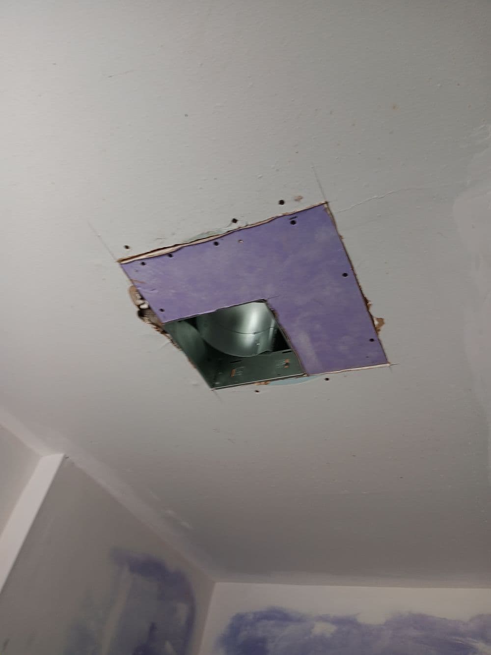 Ceiling hole with exposed vent duct in unfinished room, showing drywall edges and interior details.