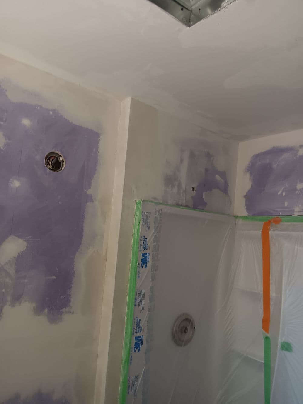 Bathroom renovation in progress, featuring drywall, plastic sheeting, and plumbing fixtures.
