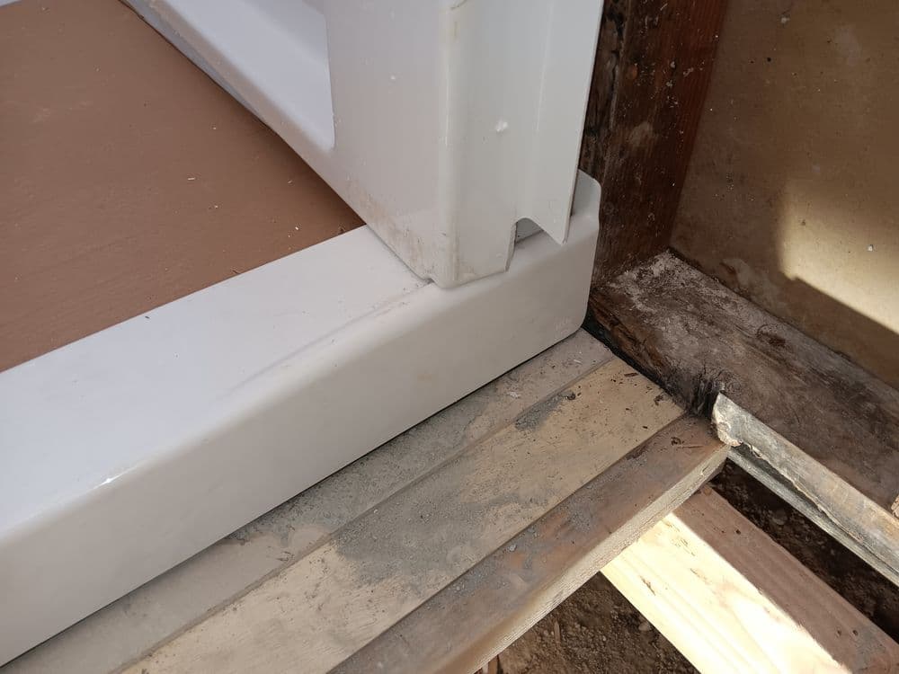 Shower base installation detail showing corner joint and surrounding floor area.