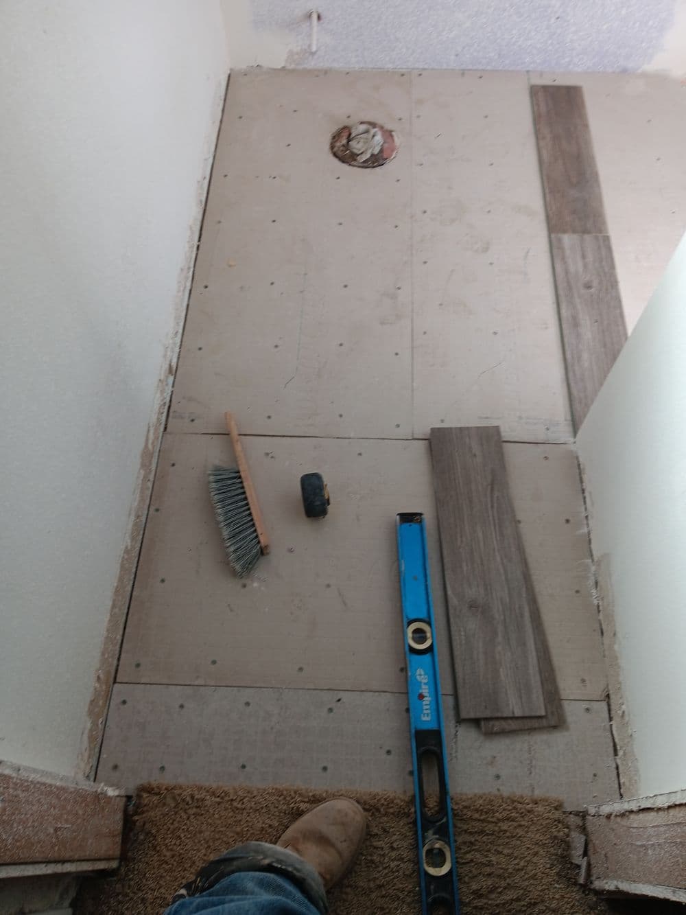 Under construction hallway with new flooring materials, tools, and leveling equipment visible.