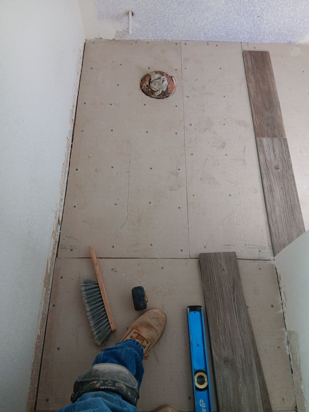 Construction site with flooring installation, showing tools, leveling equipment, and floor materials.