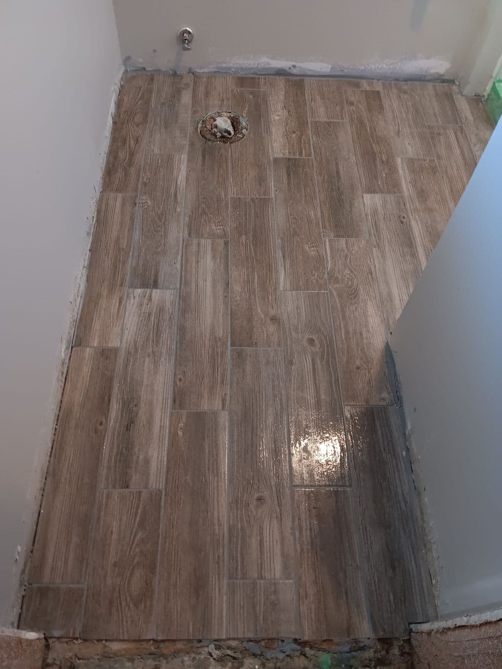 Newly installed waterproof wood-look tile flooring in a bathroom renovation.